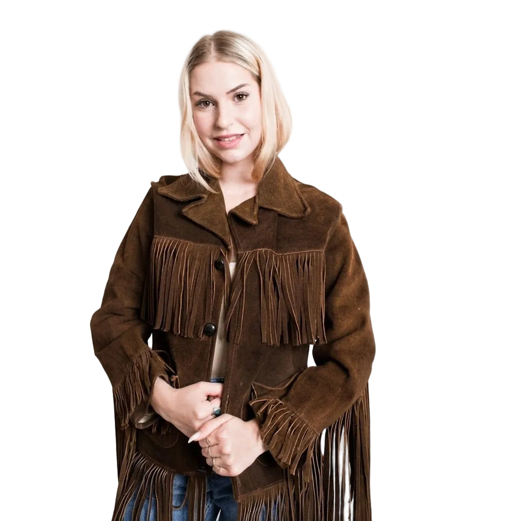 A woman with blonde hair wearing a brown suede fringe jacket, standing against a plain white background.