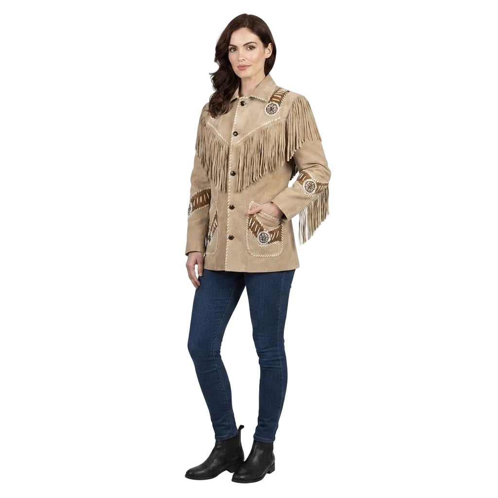 A woman modeling a beige fringed western-style jacket with embroidered details, paired with dark blue jeans and black ankle boots, against a plain white background.
