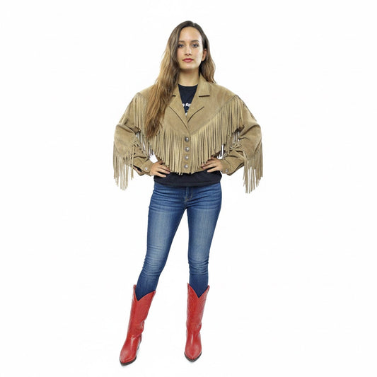 Woman wearing a beige fringe jacket, blue jeans, and red boots on a white background