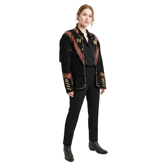 A woman modeling a black fringed jacket with paired with black trousers and boots, against a plain white studio background.