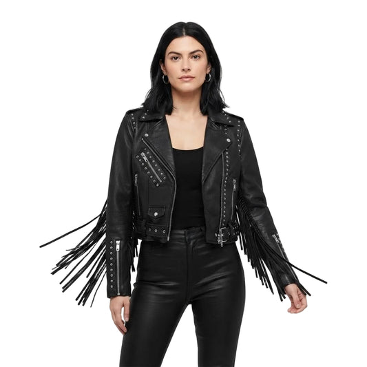 A woman modeling a black faux-leather moto jacket with long fringe details on the sleeves and studded accents, paired with black pants against a solid white background.