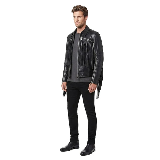 A man modeling a black leather fringe jacket over a dark gray t-shirt, black jeans, and black boots, photographed against a seamless white studio background.