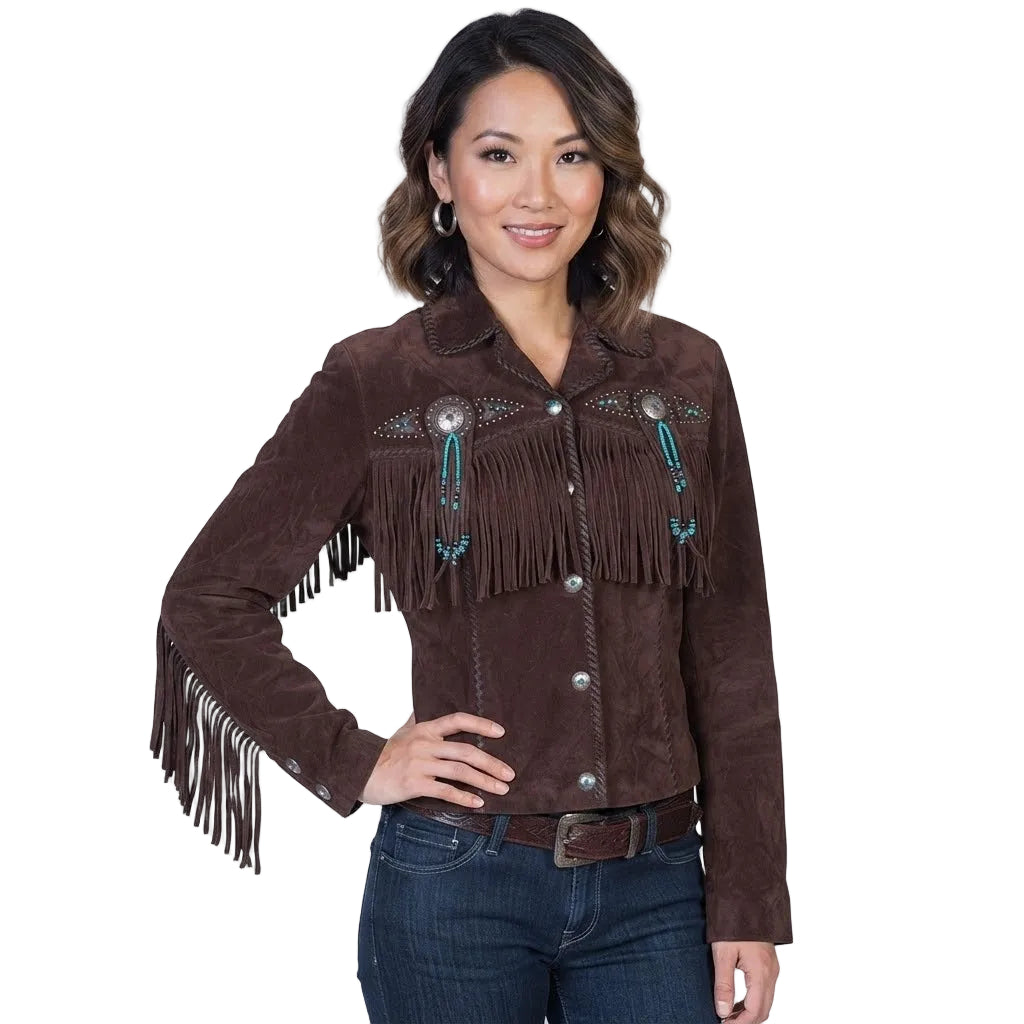 A woman modeling a dark brown suede fringe jacket with turquoise beadwork and silver conchos, paired with dark blue jeans against a plain white background.