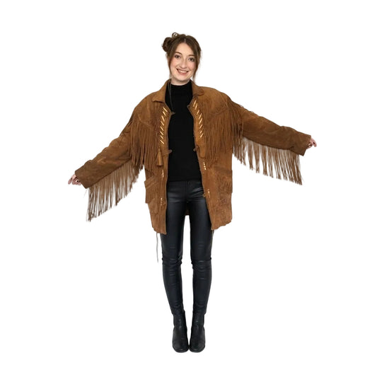 A woman modeling a brown suede fringe jacket over a black turtleneck and black leather pants, against a plain white studio background.